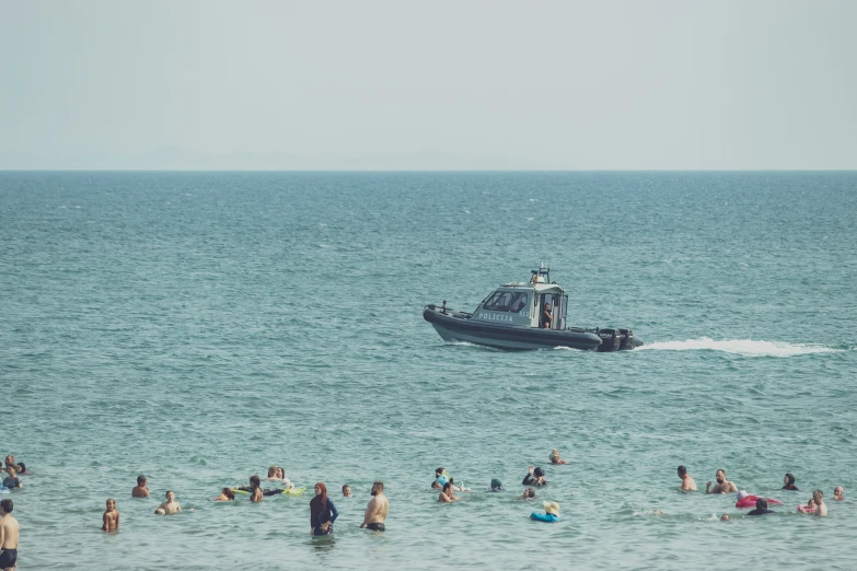 large group of people in the ocean near a boat with people riding in the water