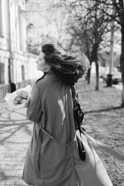 a woman walking down a street while holding a paper