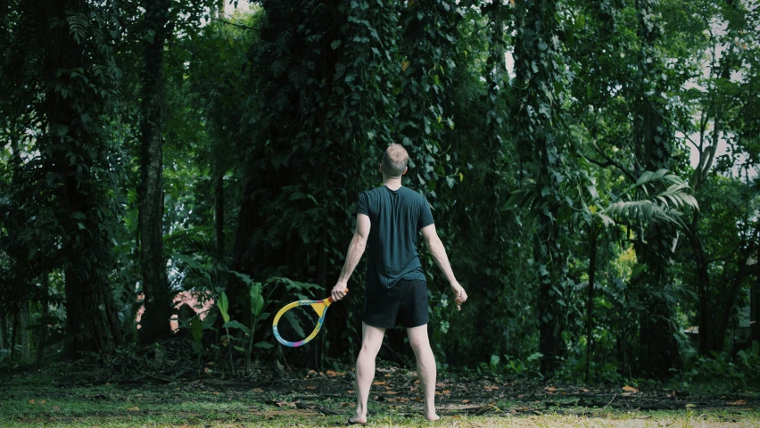 the man stands on the ground with two colorful tennis rackets