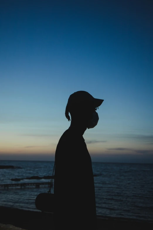 the silhouette of a man who is wearing a face mask on a beach