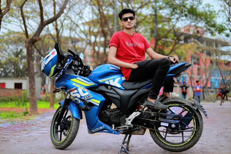 a man sitting on top of a parked blue motorcycle