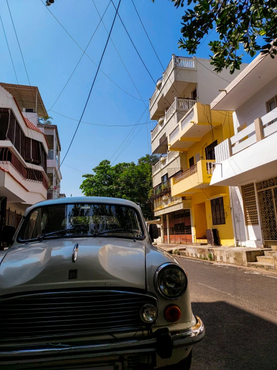 an old car on a busy street with apartments in the background