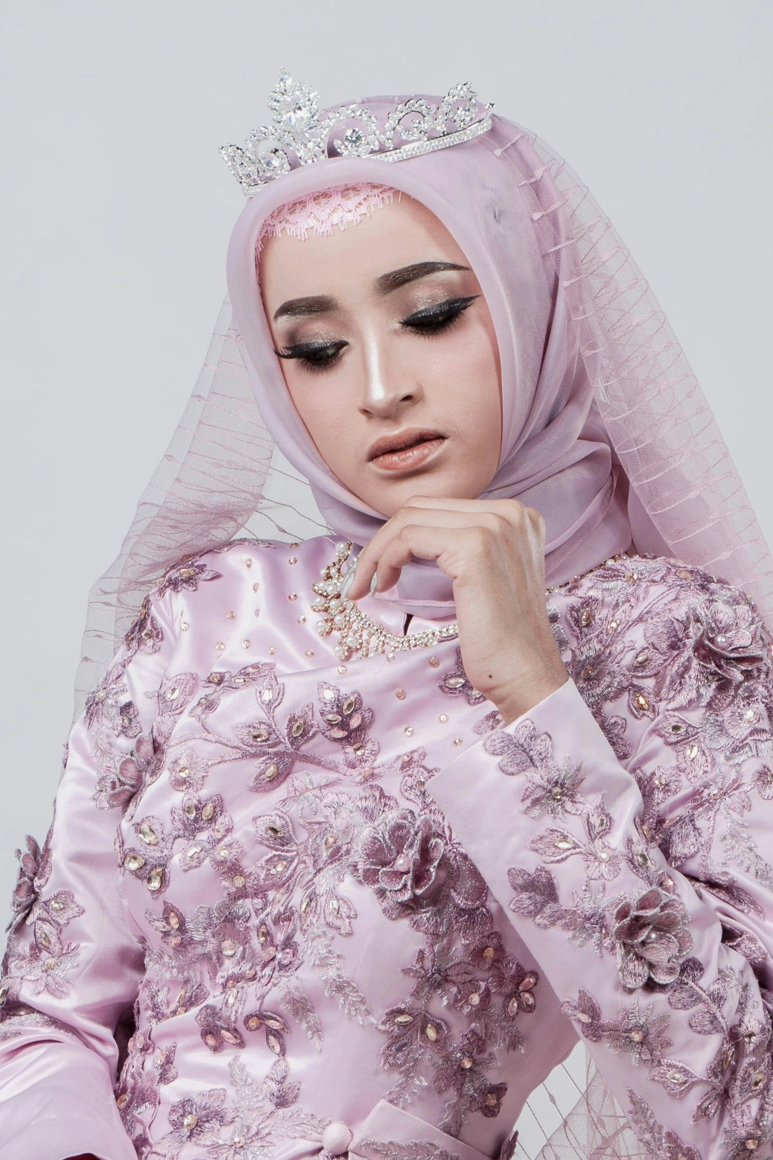 this model poses for the camera wearing a pink hijab and tiara