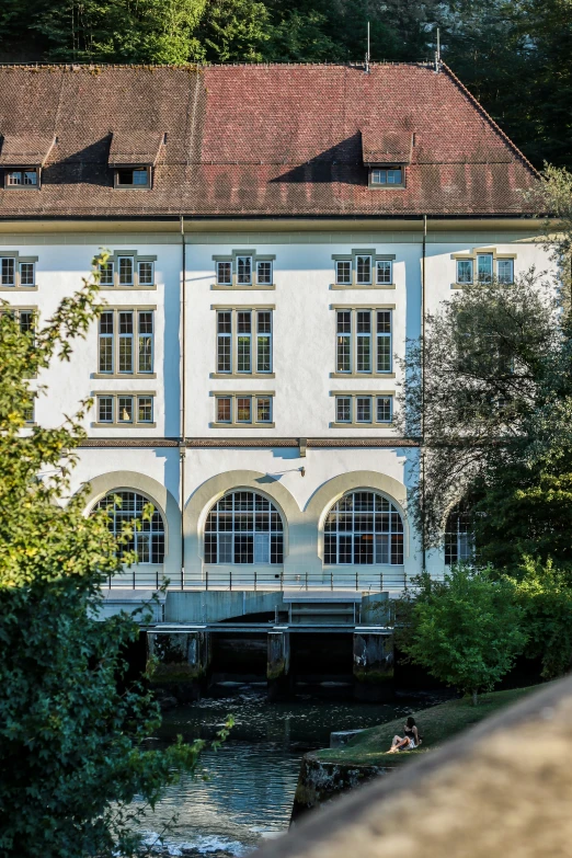 a tall white building with three stories and a river running under it