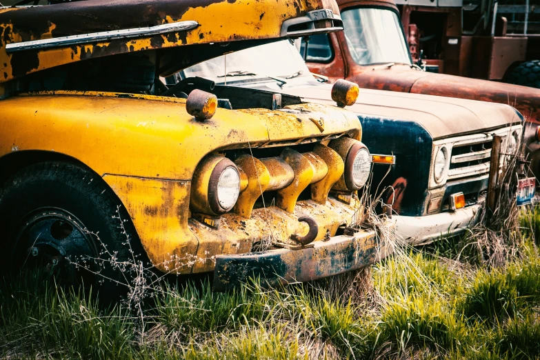 two old trucks sitting in the grass outside