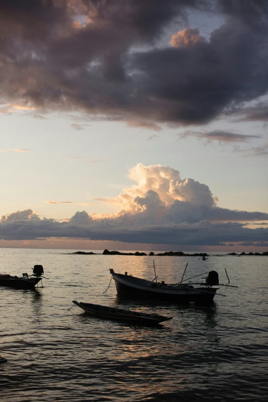 boats sitting on top of the ocean at sunset