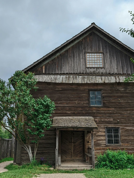 an old wooden building has a fence and some trees