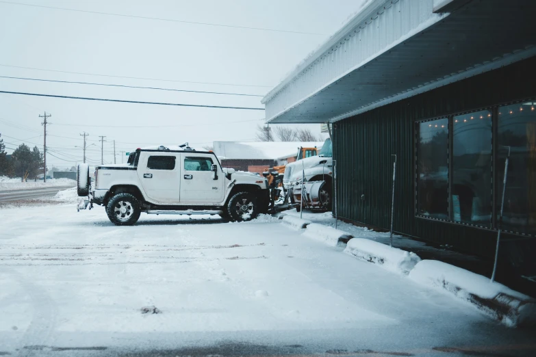 a white truck parked in the snow next to a building