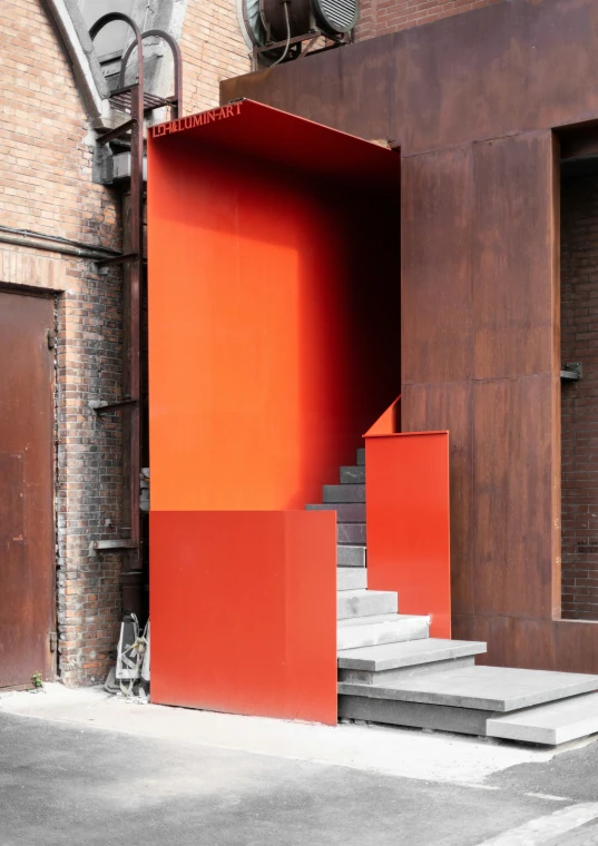 a red outdoor structure next to some steps and a brown building