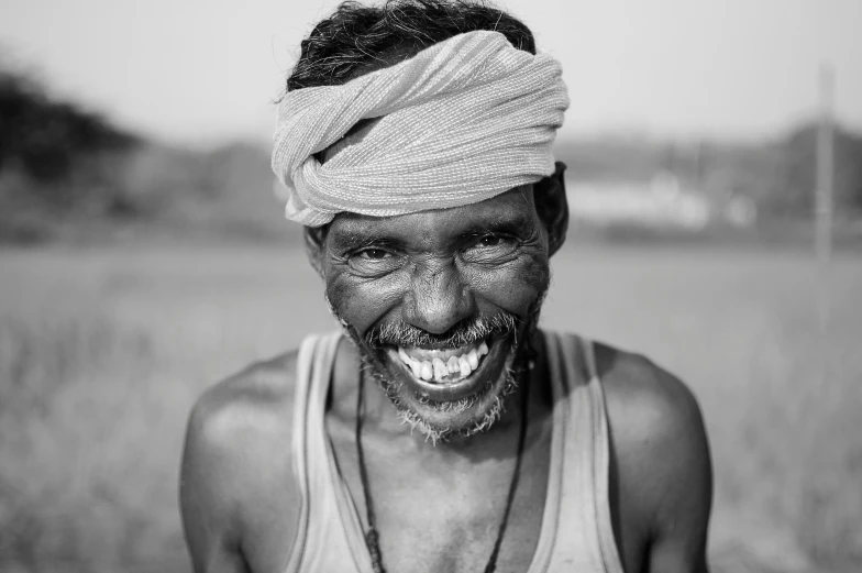 an african man with some dirty teeth in a field