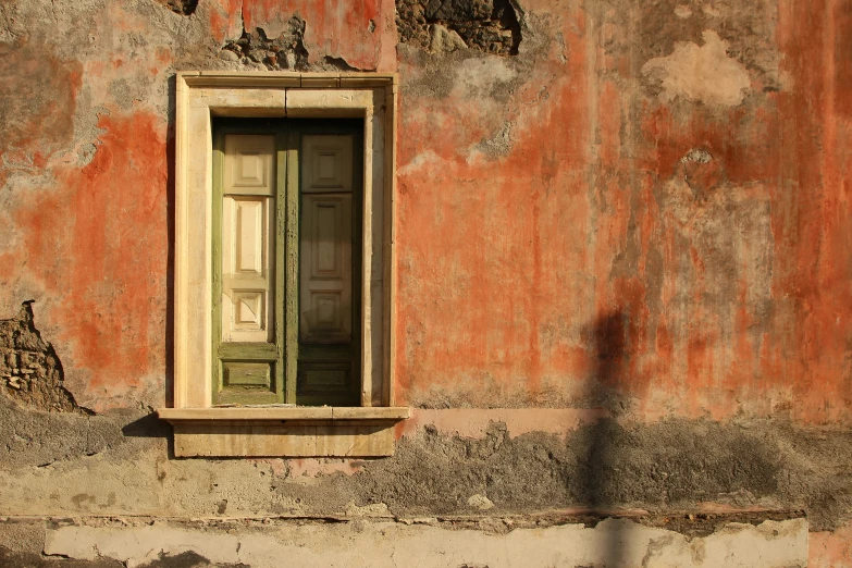 an old, stained and stuccoed building with one open door