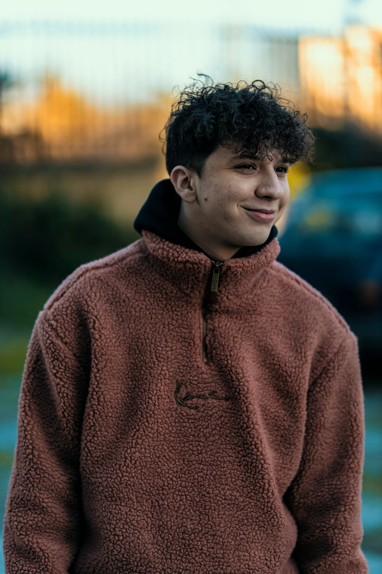 a man smiles with dark hair as he holds a skateboard