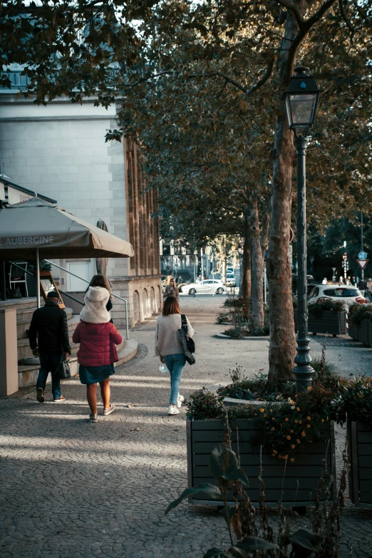 several people walking down a sidewalk near trees