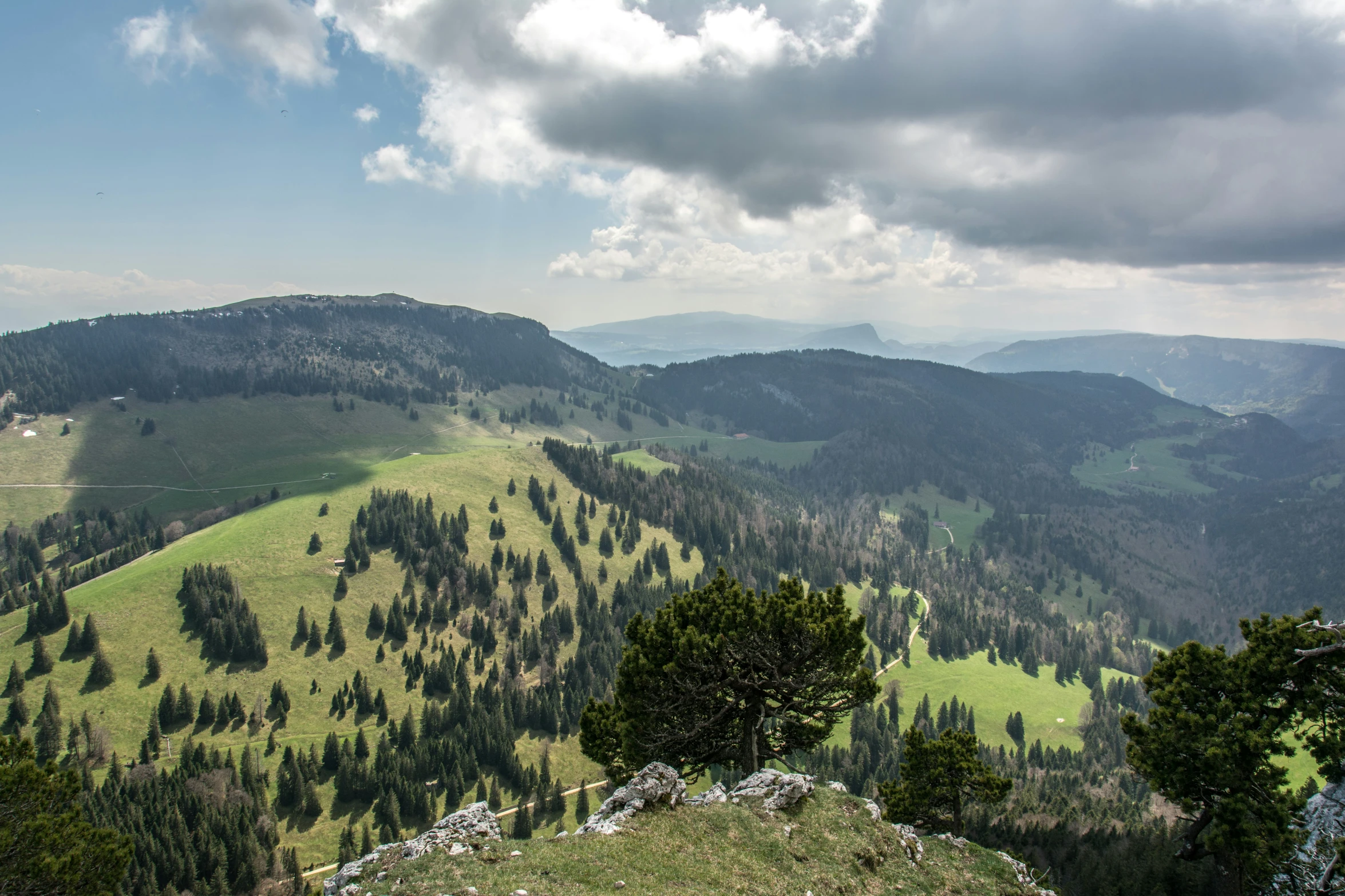 some mountains are filled with green trees and clouds