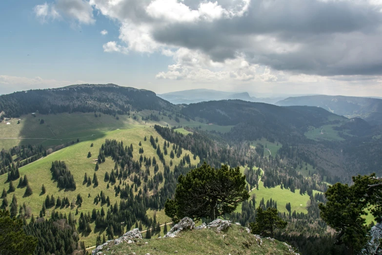 some mountains are filled with green trees and clouds