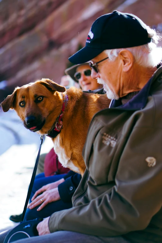 an older man and woman petting a dog on the street