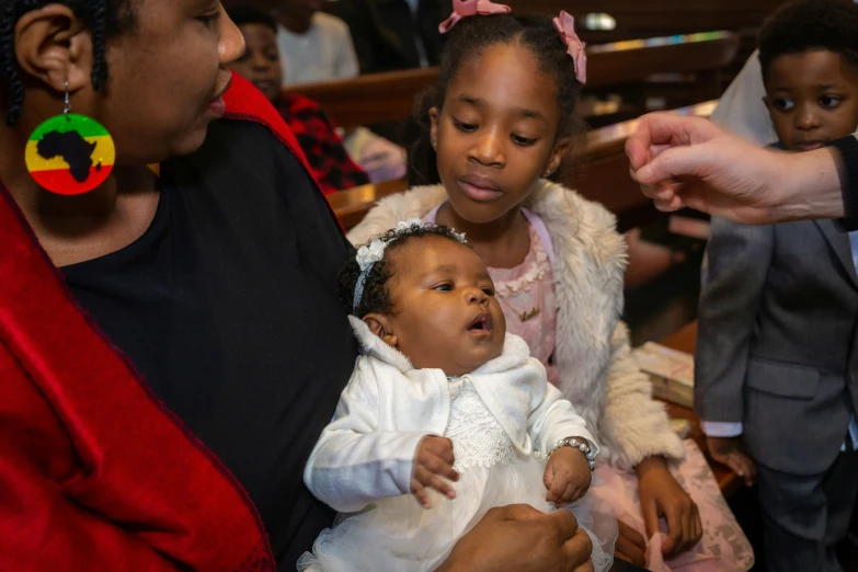 several children are sitting down with a toddler