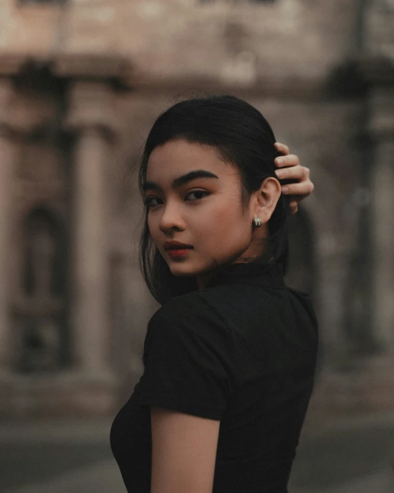 a woman in black shirt posing near stone building