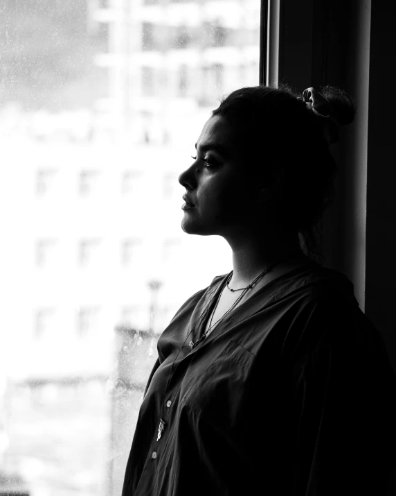 a woman standing by the window looking outside