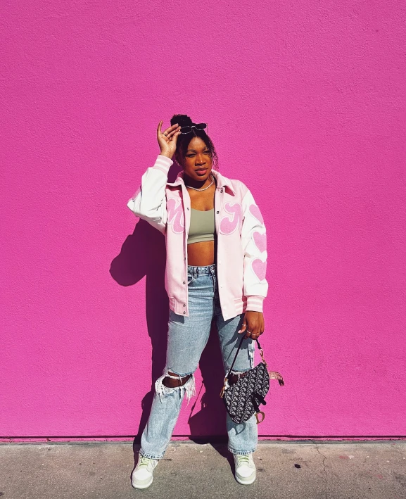 a young woman wearing ripped jeans standing next to a pink wall