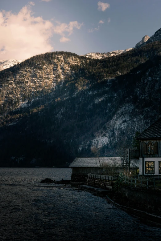 house sitting on the shore of the lake by a mountain