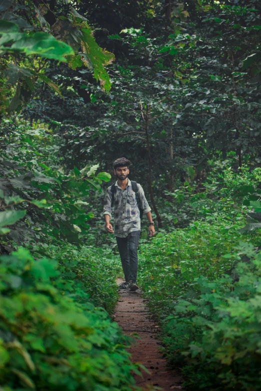 a young man hiking through the woods wearing a backpack