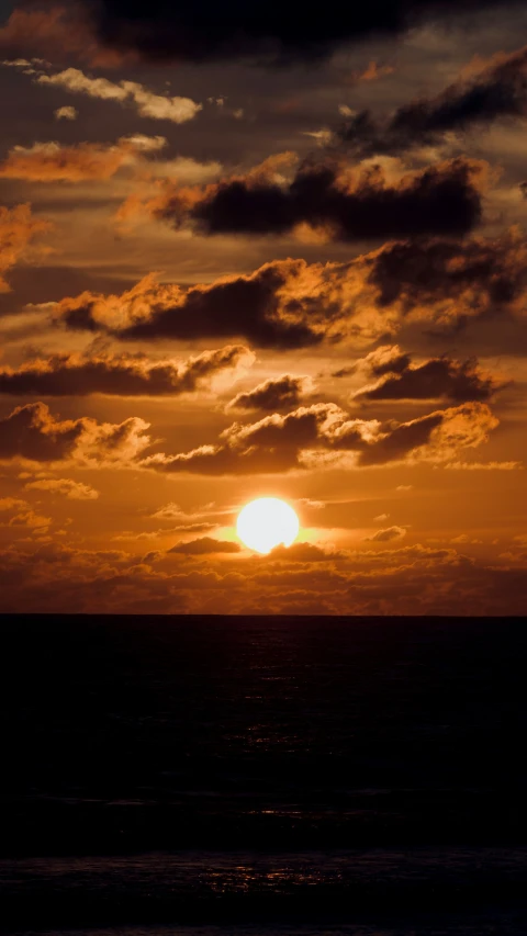 an orange sunset and a black silhouette over the ocean