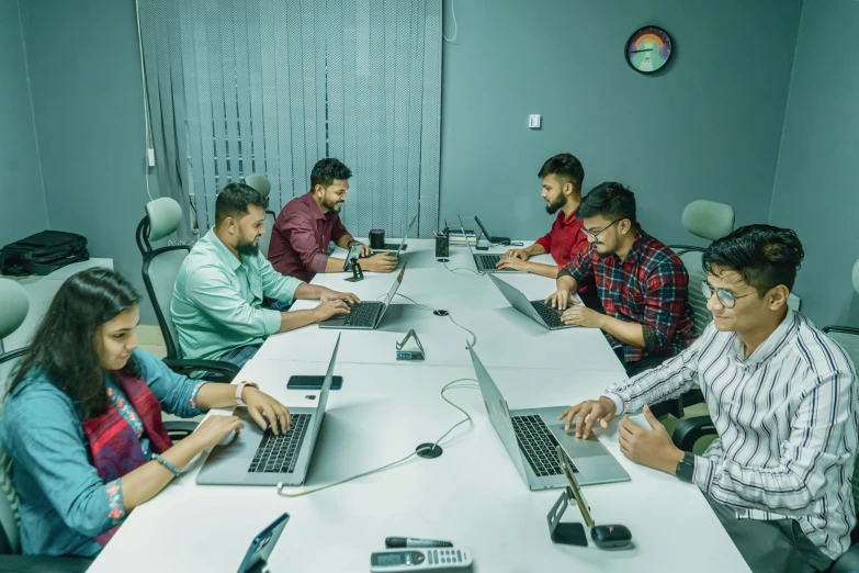 people sitting around a table using laptops