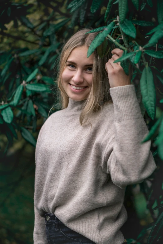 a beautiful woman standing by some plants posing for a picture