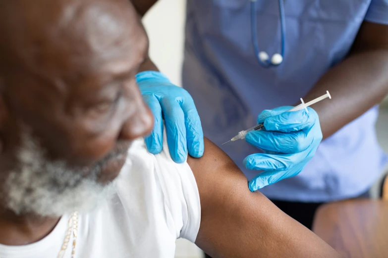 a nurse in blue gloves is performing an injection to the arm of a man