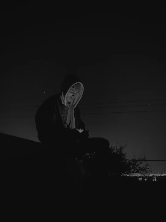 a man sitting on top of a roof at night