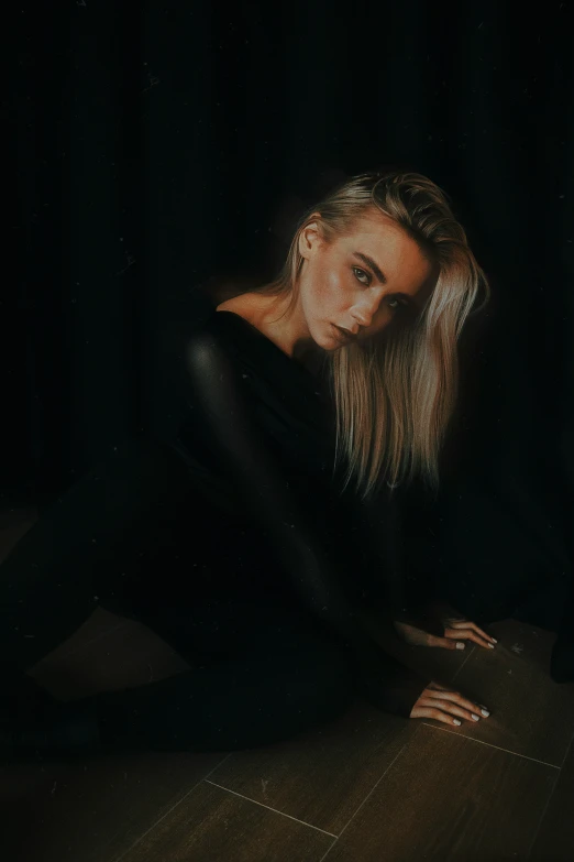 a girl sitting on a floor in a black dress