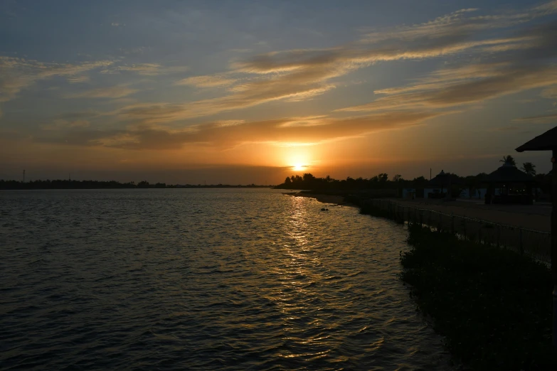 a sunset reflects on the water behind the pier