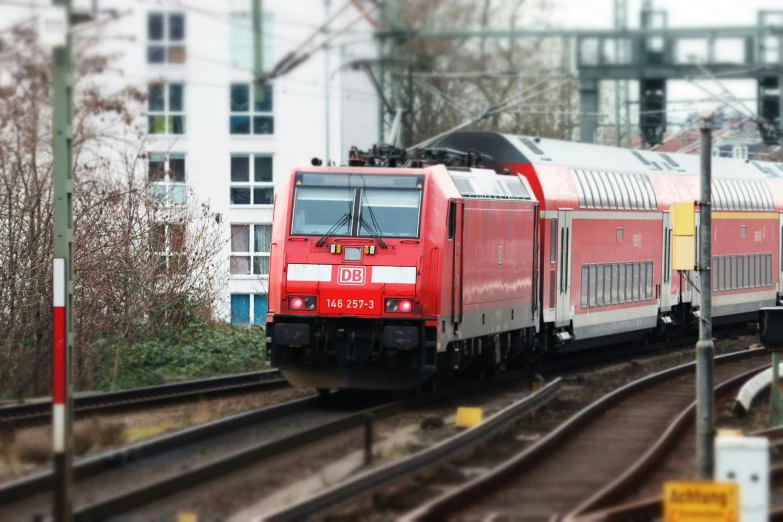 red train on track at an intersection near building