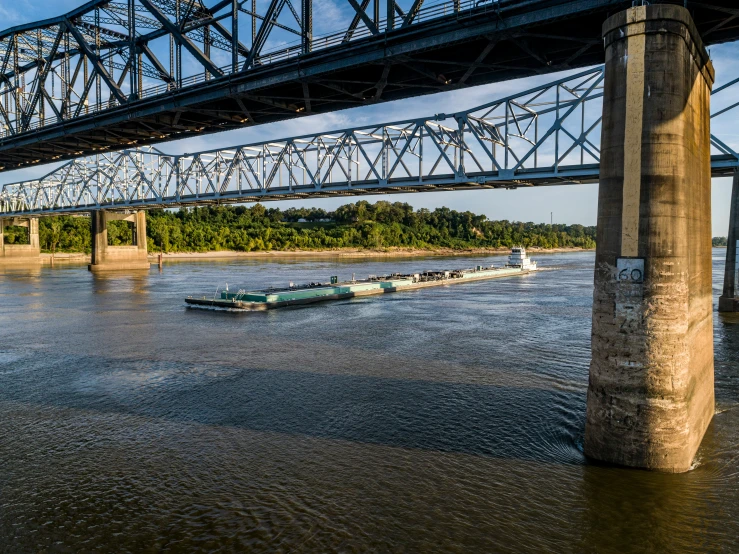 a barge on water underneath a metal bridge