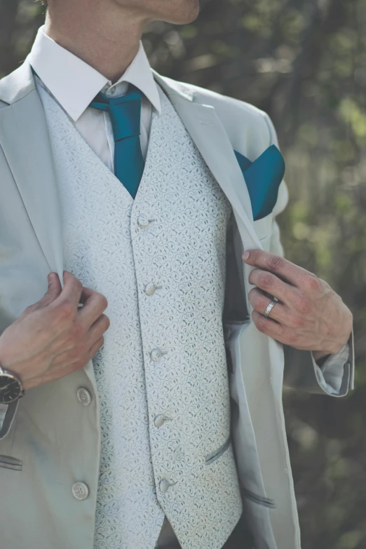 a man in a jacket and tie adjusting his white jacket