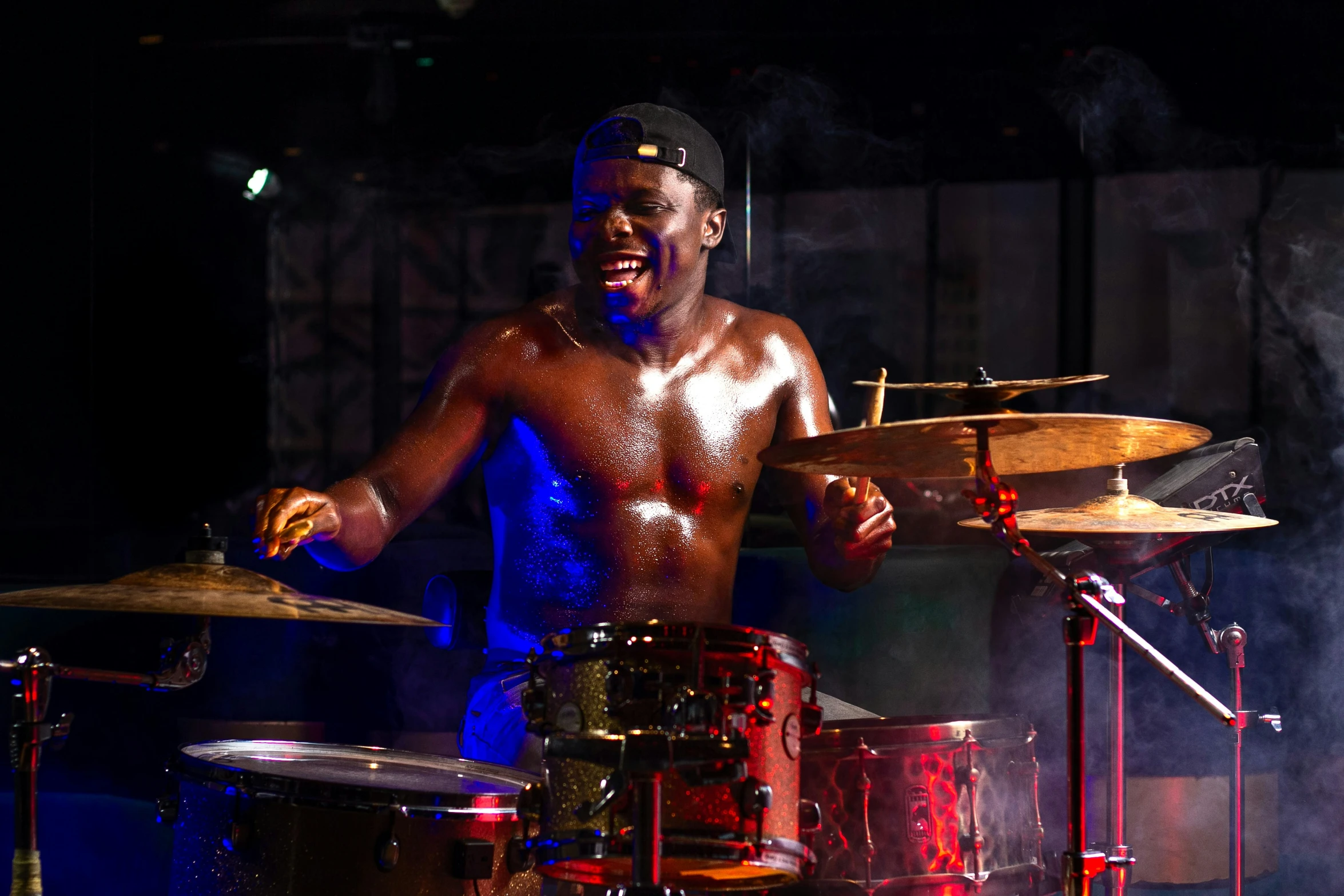 a young man playing the drums with smoke coming from the drumsticks