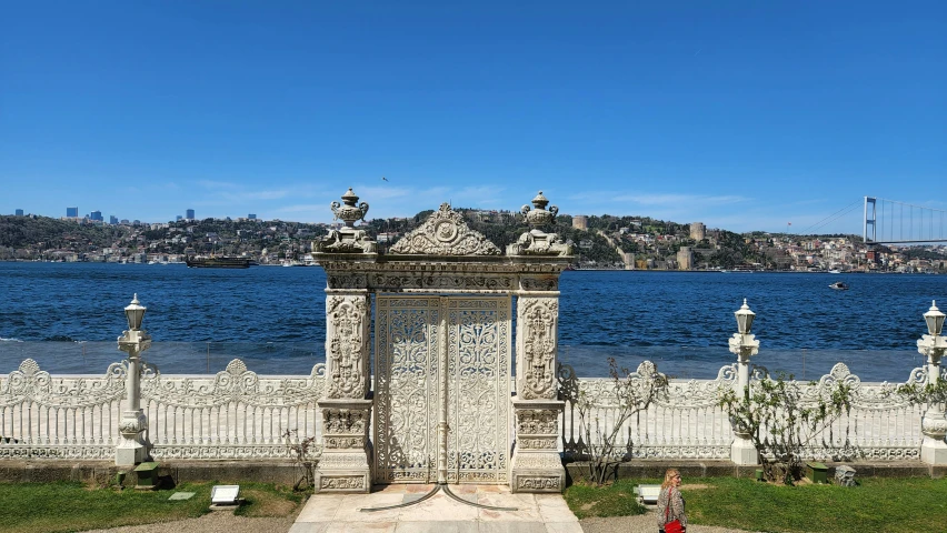 a white fence near the water in front of a large body of water