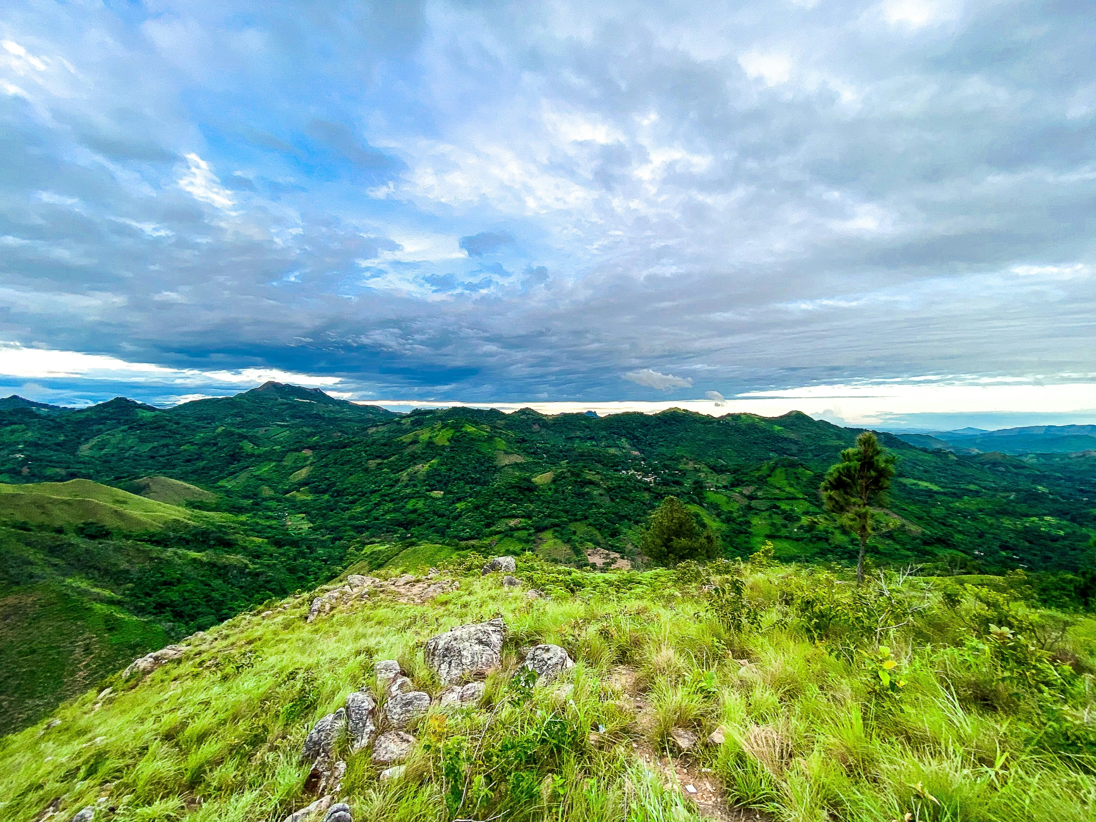 a mountain scene with a cloudy sky and some trees