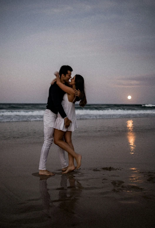 a man and woman emcing on the beach