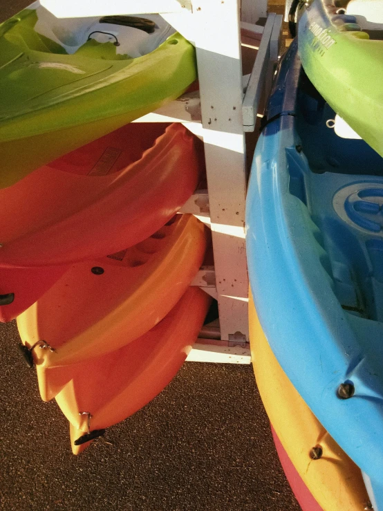 some colorful kayaks are stacked up on the ground