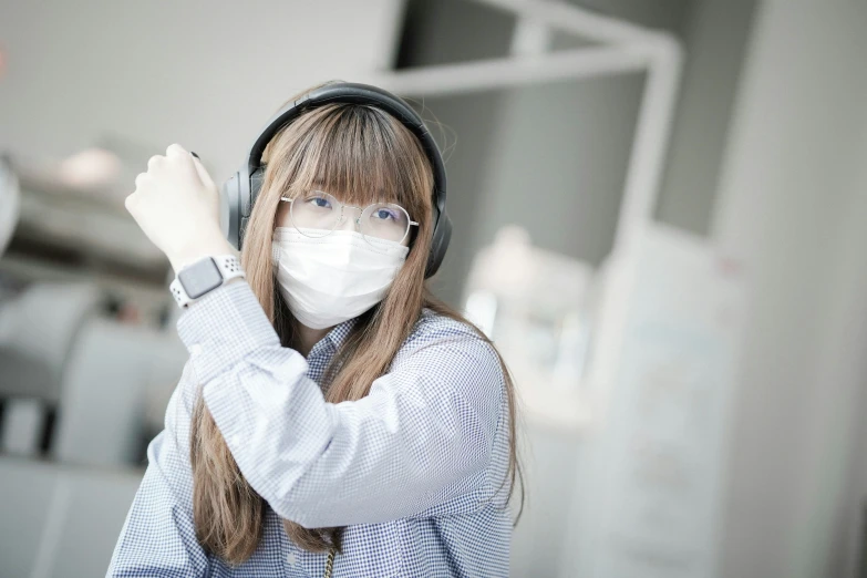 a woman in a medical mask is holding a headphones