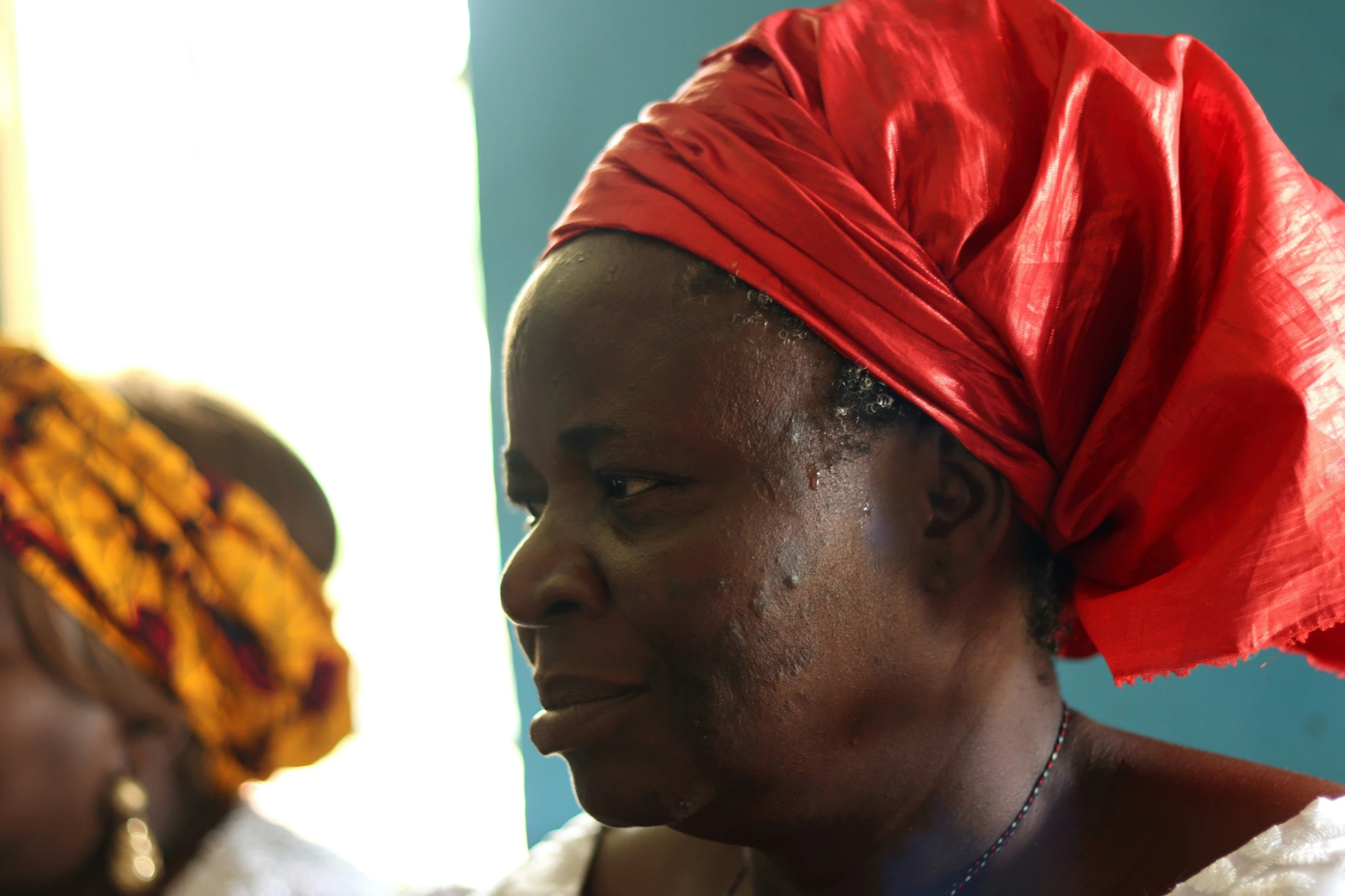 a woman with a red head wrap is sitting near another women