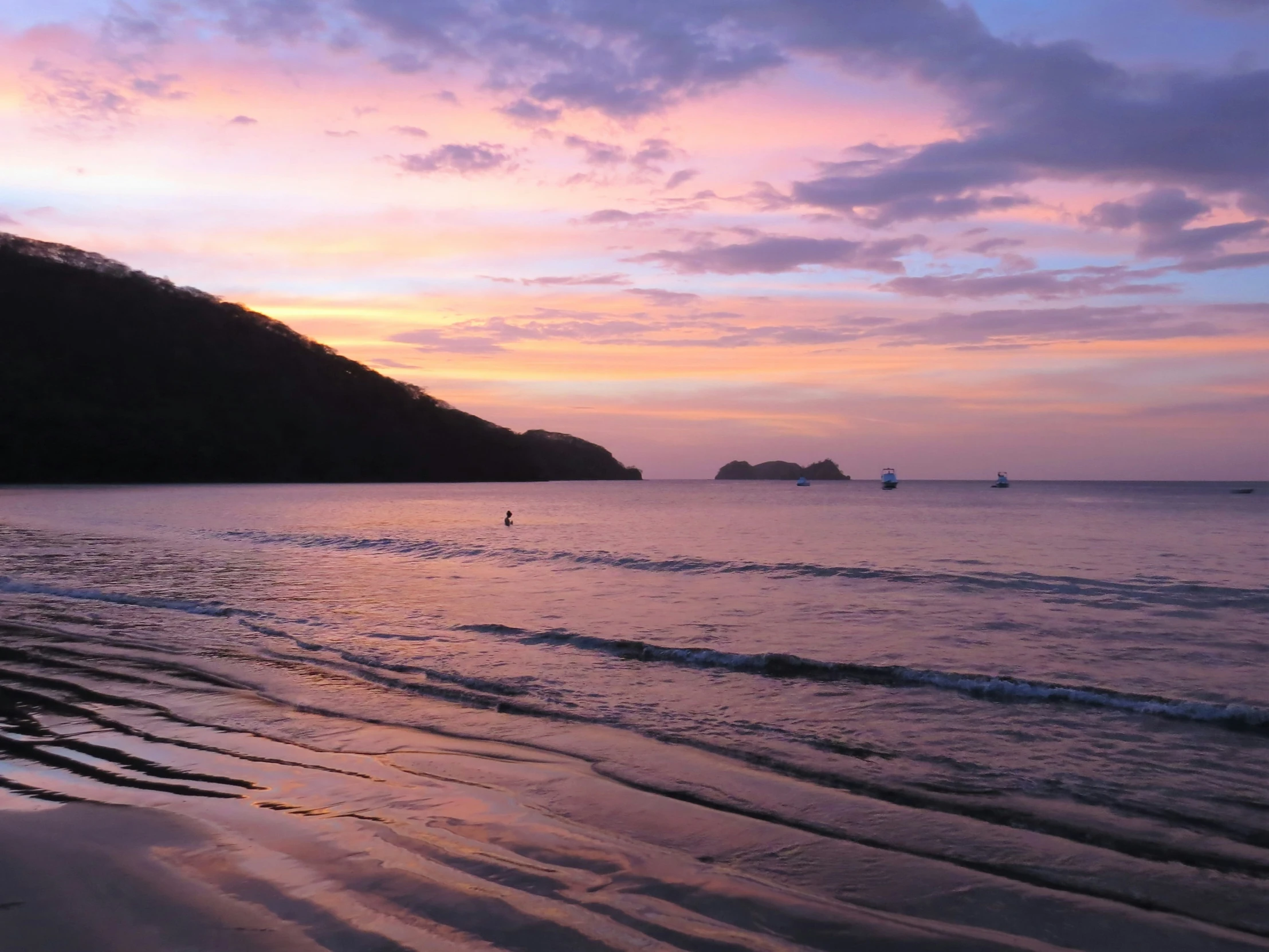 a beach filled with lots of water and a small hill