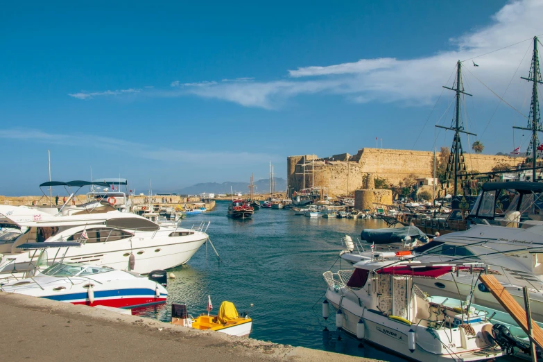 many boats are docked in the bay near a castle