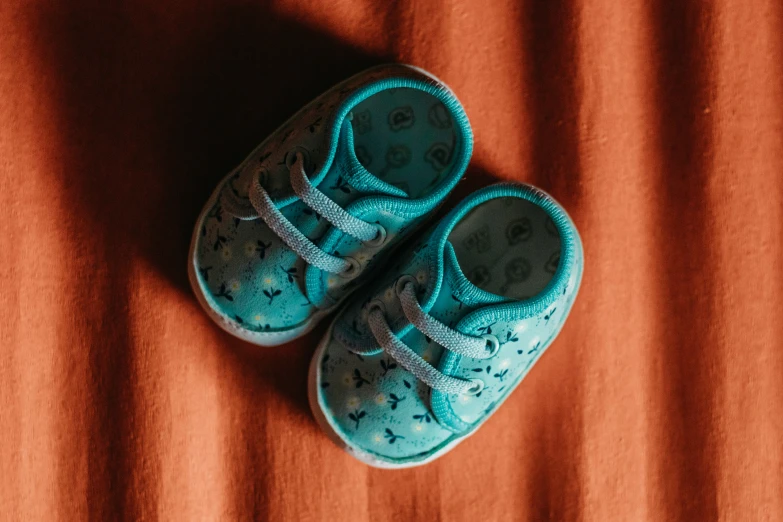 two blue shoes are placed on top of an orange blanket