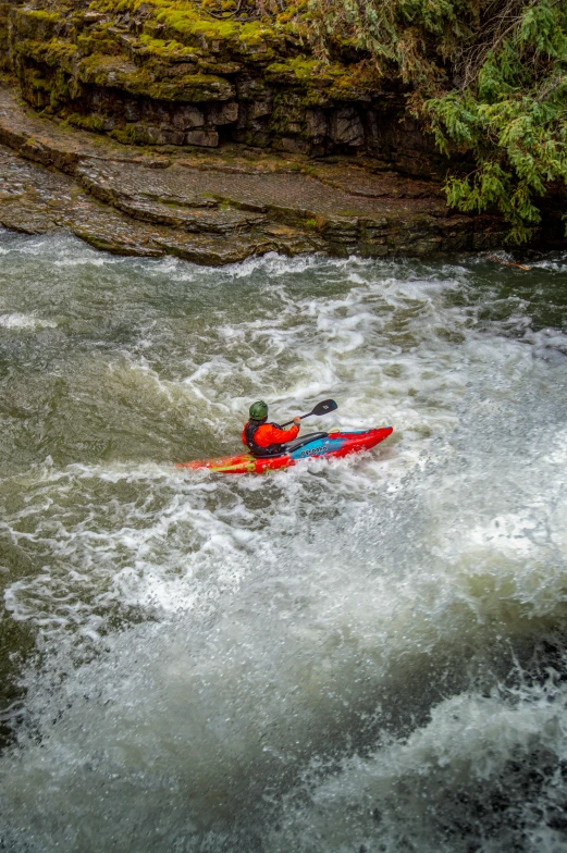a man in a red kayak going down a waterfall