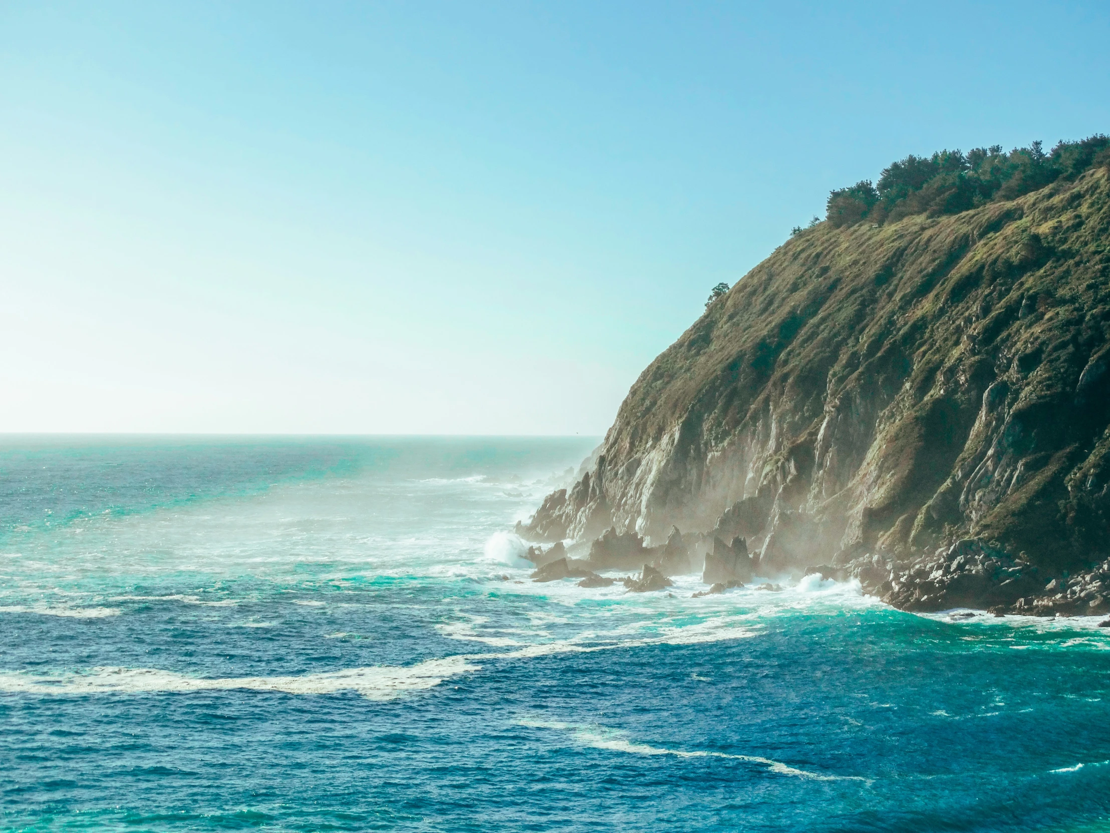 a cliff near the ocean on a sunny day