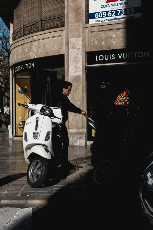 a man standing next to a white scooter near a building