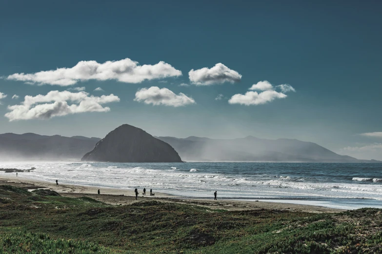 some people are standing on the beach near the water